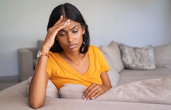 Stressed woman leaning her forehead on her hand.